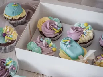 Bunte Cupcakes in einer weißen Box auf Tisch.